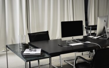 Modern minimalist workspace with two Apple iMacs and marketing books, embodying the sleek efficiency of social media success.