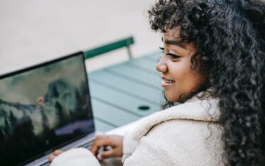 Smiling woman enjoying her SEO success story while working on a laptop outdoors