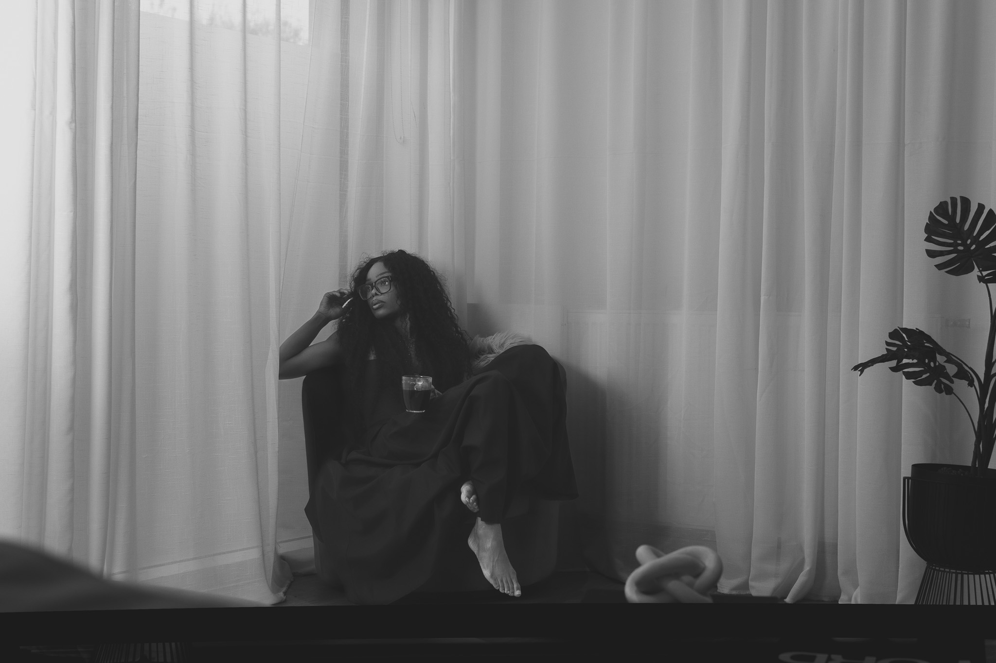 Bess Obarotimi sitting peacefully by white curtains, holding a drink, reflecting — promotional image for the I AM Success book.