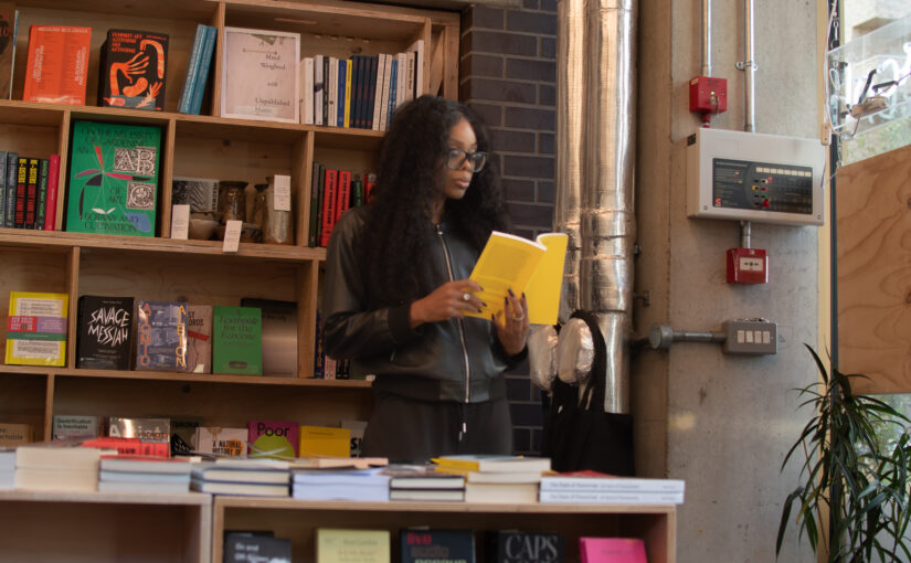 Bess Obarotimi reading in a bookshop while reflecting on identity and manifestation for her I AM Success blog post.