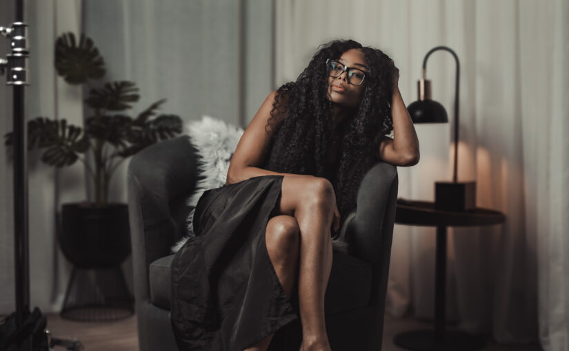 Bess Obarotimi seated in a dimly lit studio, reflecting during the Spiritual Authenticity I AM Success Mini-Series.