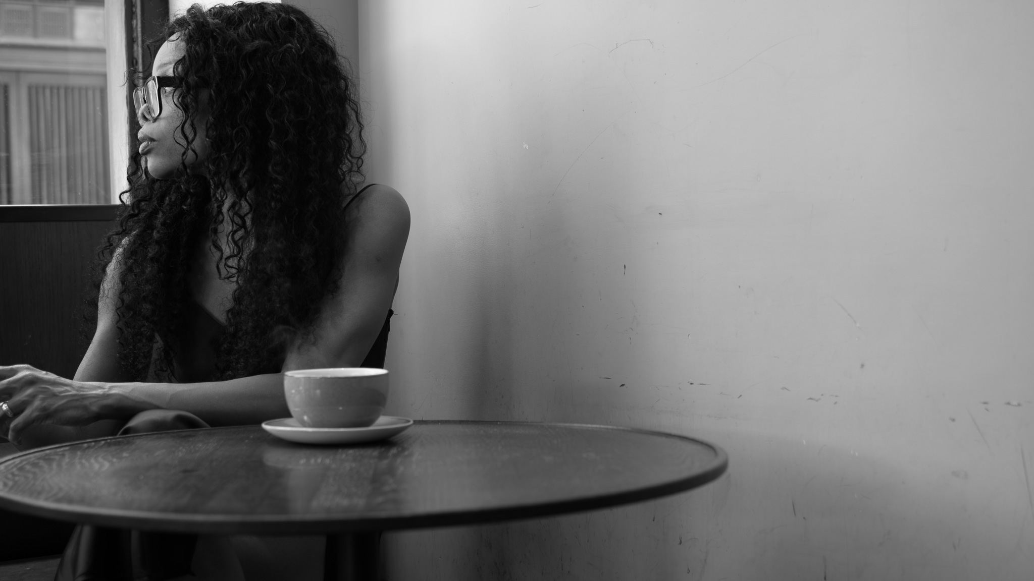 Woman seated at a table in a café, looking out of a window, used to accompany an article on decision-making authority and responsibility.