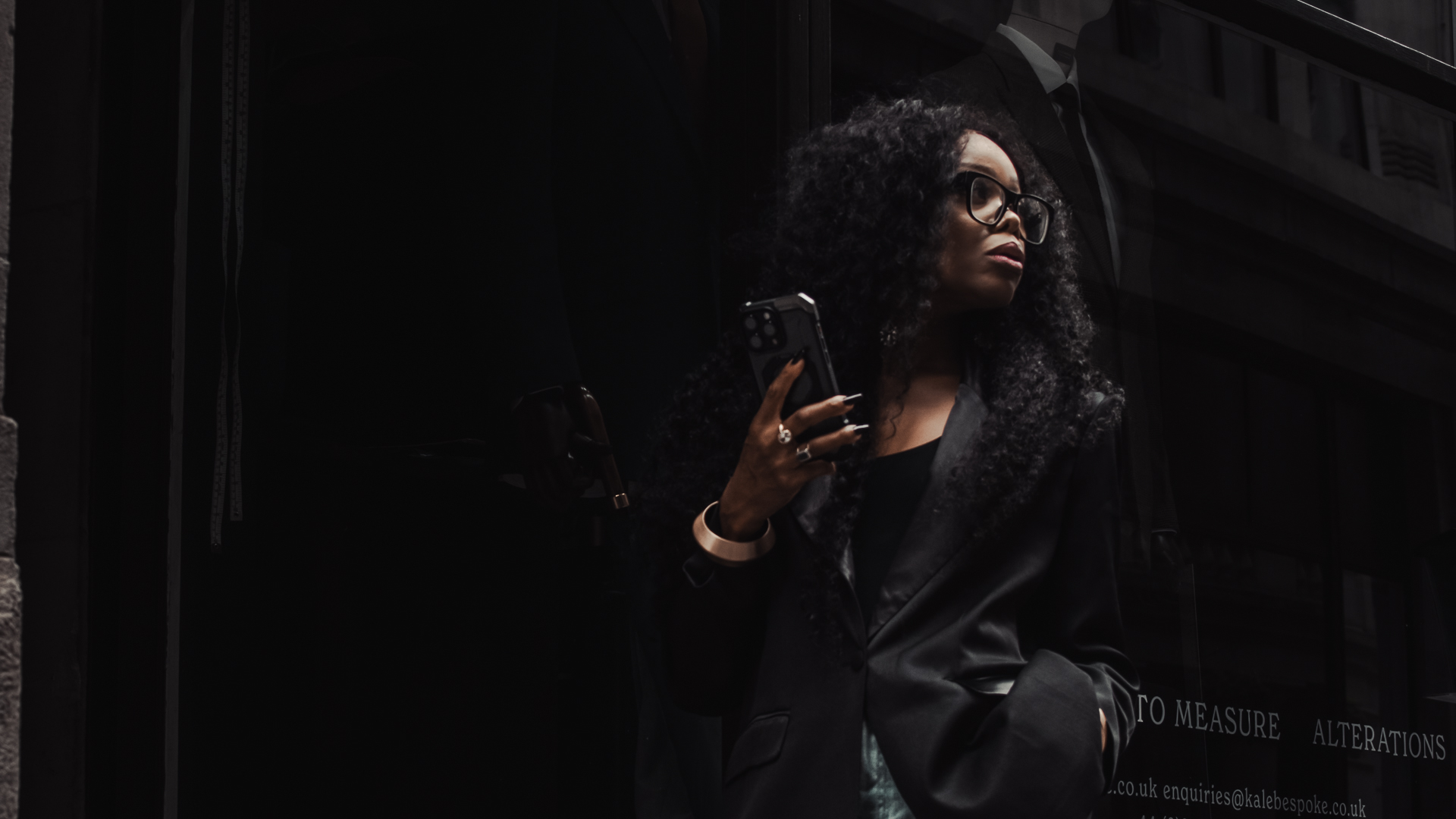 Professional woman in a dark urban setting using her phone, representing the AI productivity divide and modern workplace performance differences.