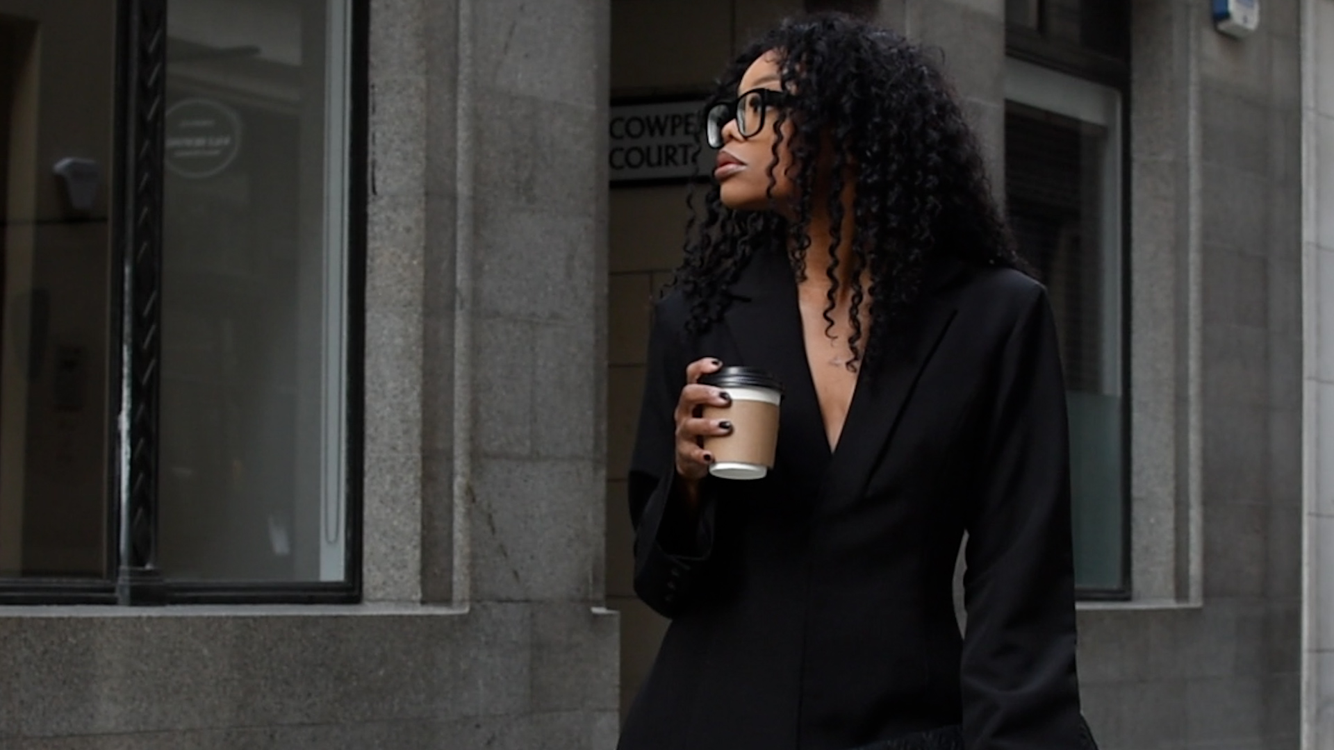 Professional woman holding coffee outside office building, representing leadership, decision making, and AI governance in practice