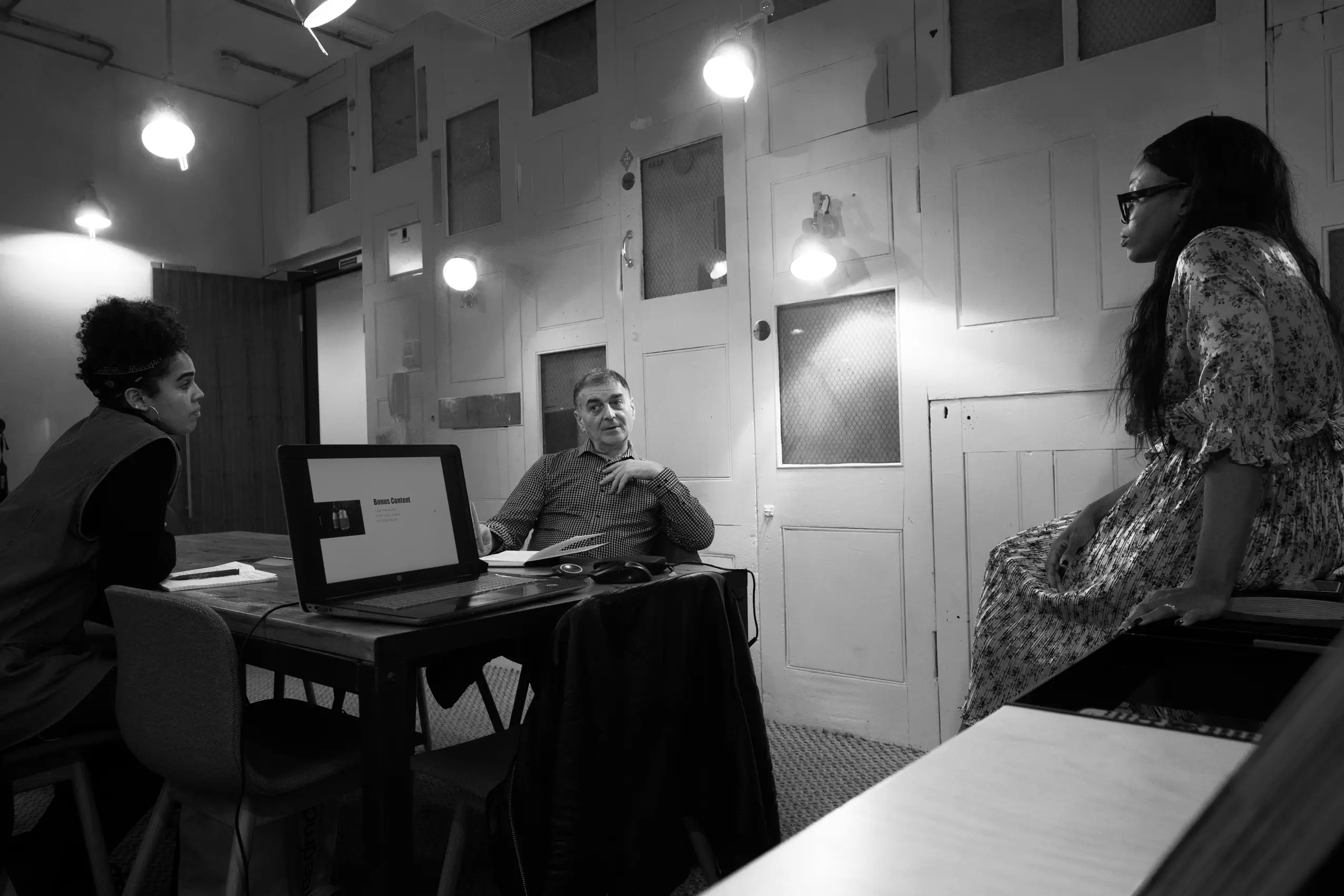 Black and white photo representing clarity in decision making, showing three professionals in a meeting discussing a presentation in a quiet workspace.