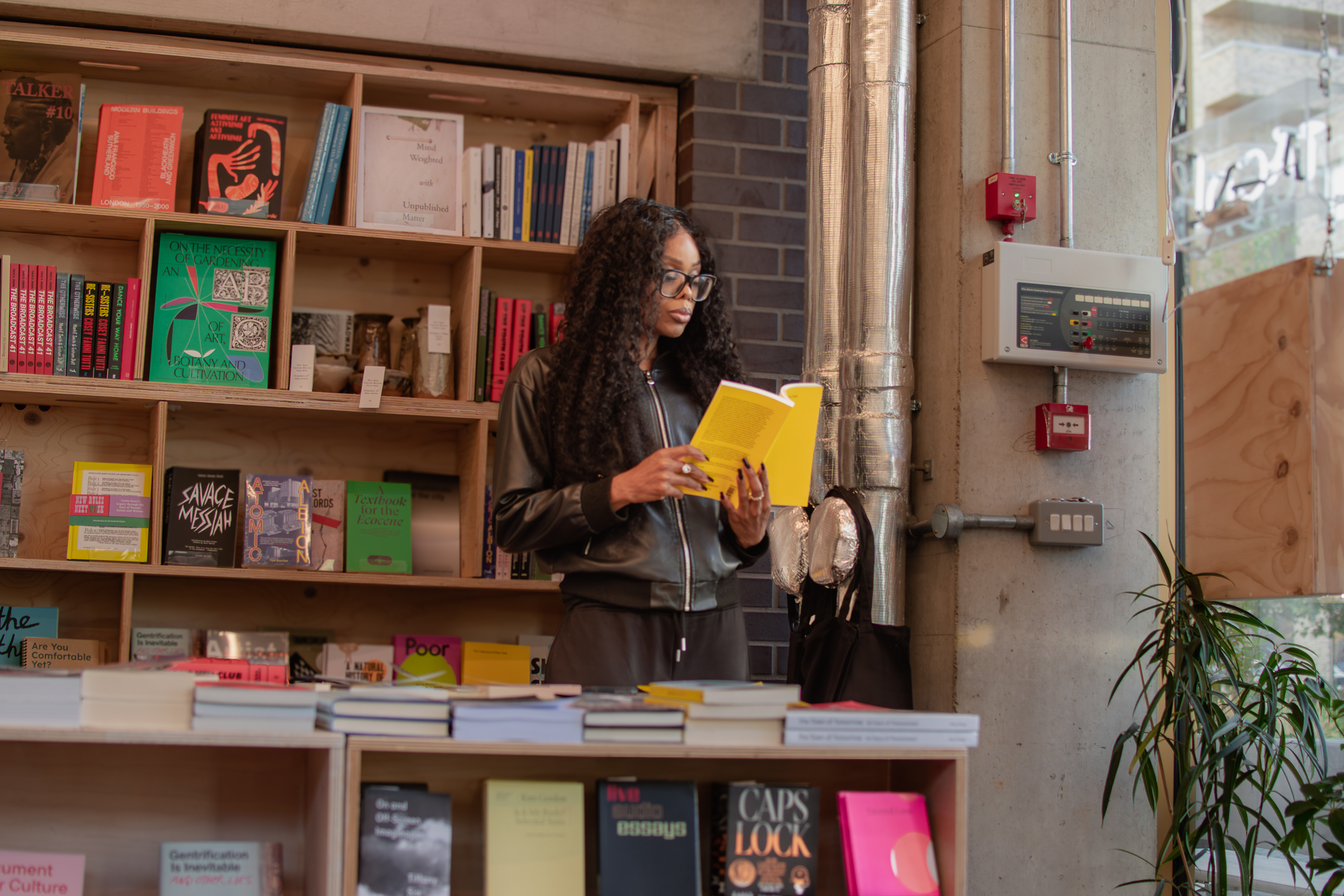 Woman reading a yellow book in an independent bookstore, illustrating organisational leadership, decision-making uncertainty and the illusion of control in complex organisations.